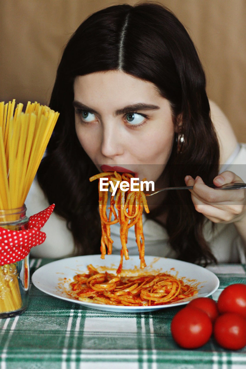 woman-eating-pasta-in-restaurant-id-144112063