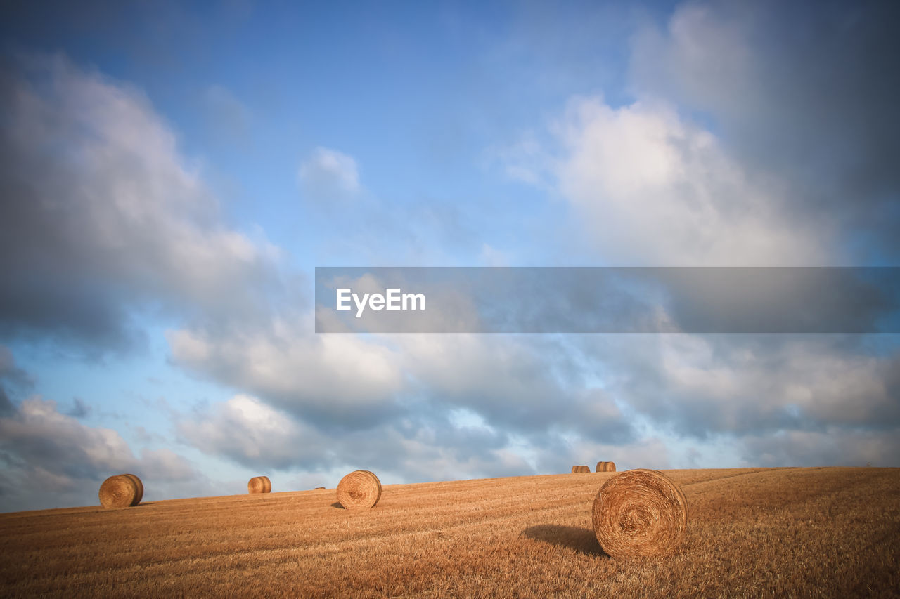 Hay bales on field against sky