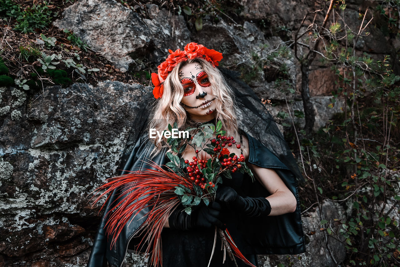 Closeup portrait of calavera catrina. young woman with sugar skull makeup and red flowers. dia 
