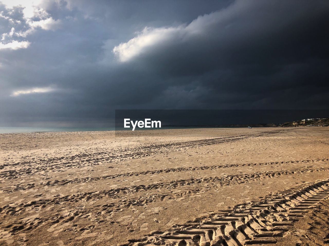 Scenic view of beach against stormy sky