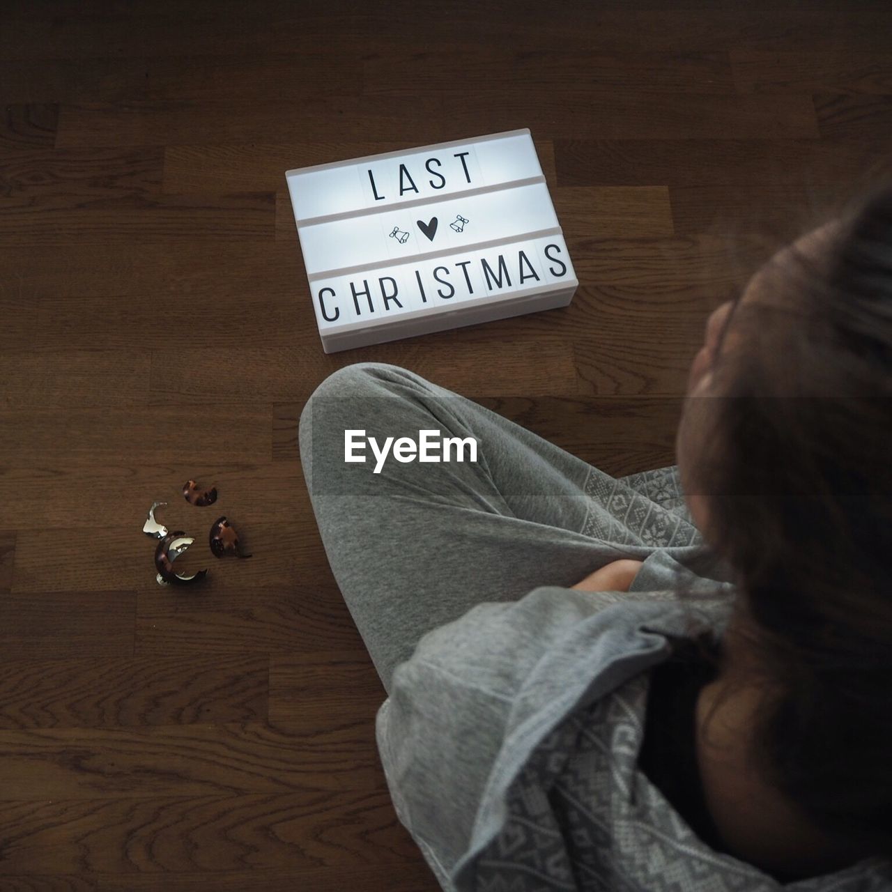 High angle view of woman sitting with christmas decoration on hardwood floor at home