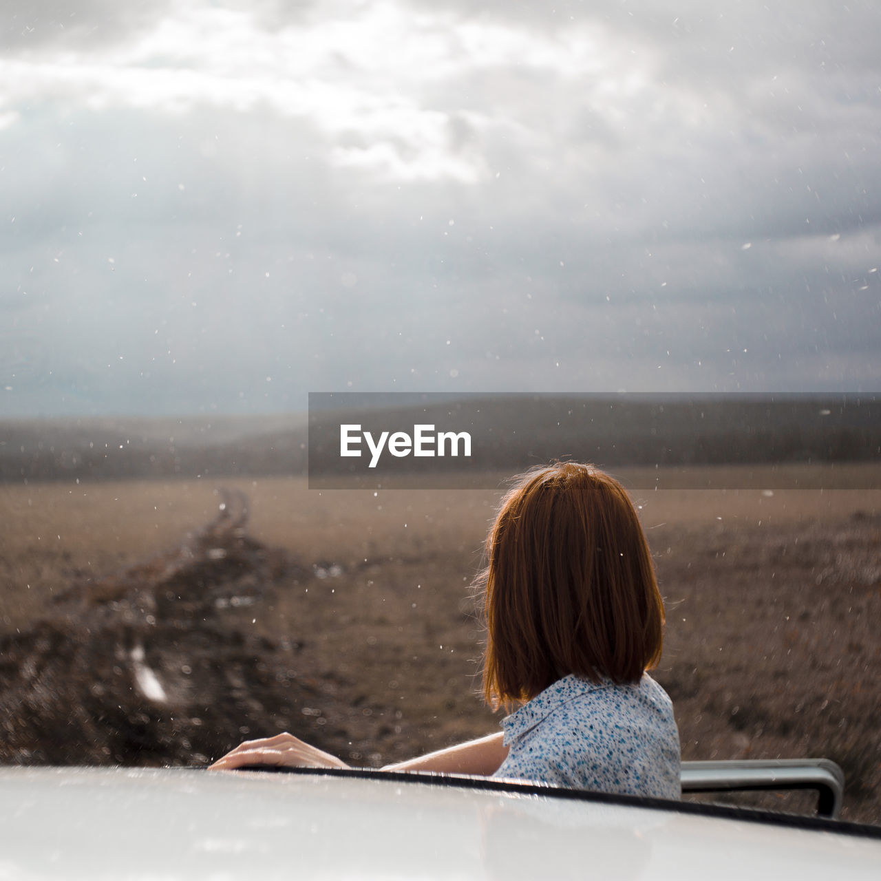 Woman looking at view while standing by car