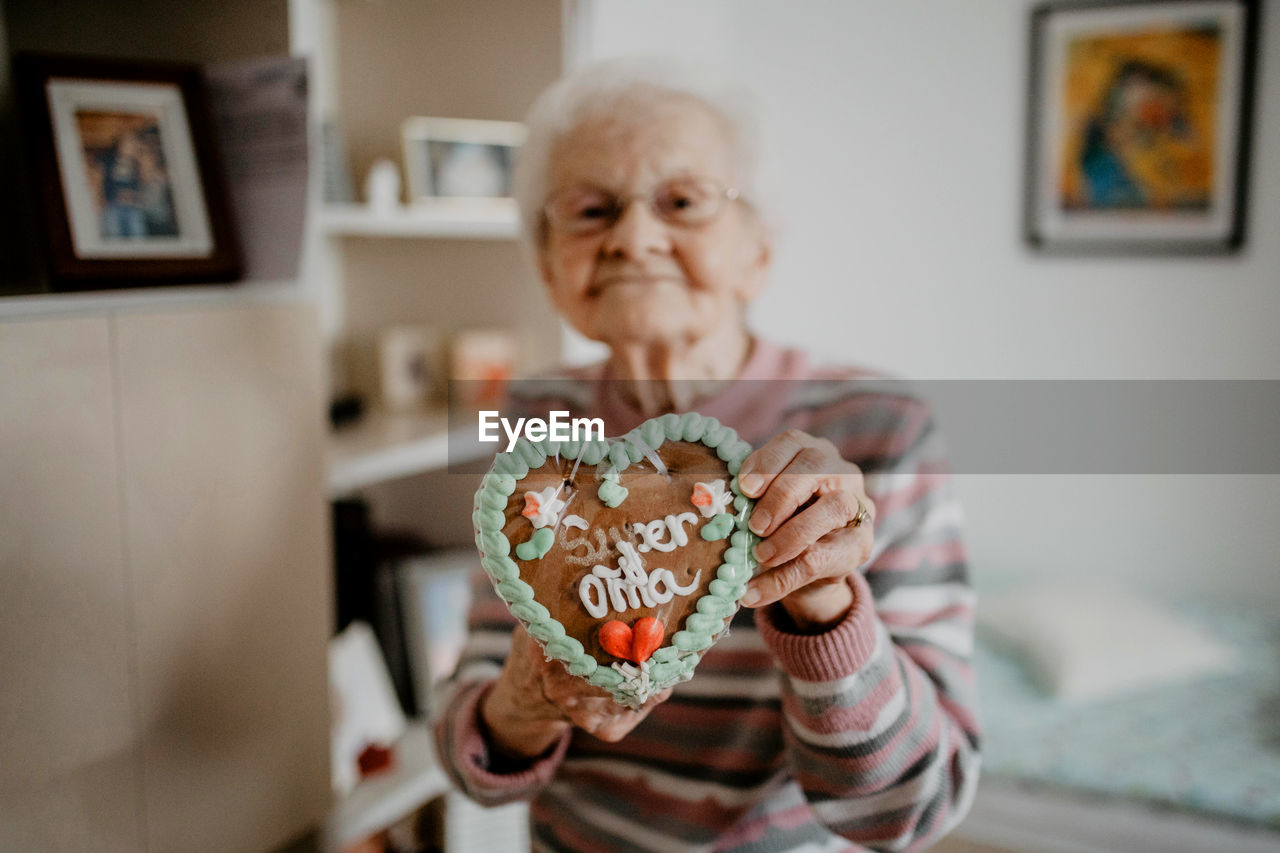 Portrait of senior woman holding gingerbread cookie at home