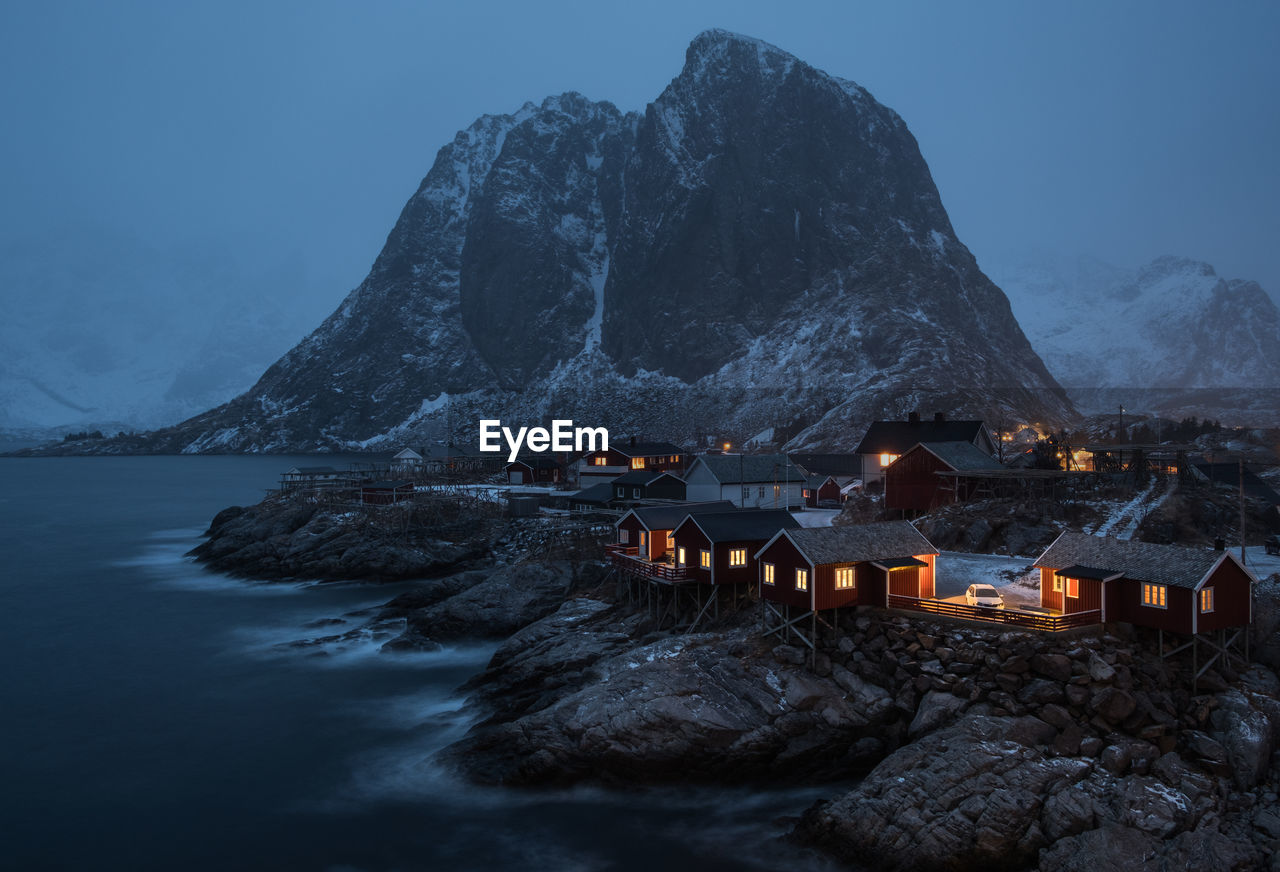 View of lake and town against mountains during winter