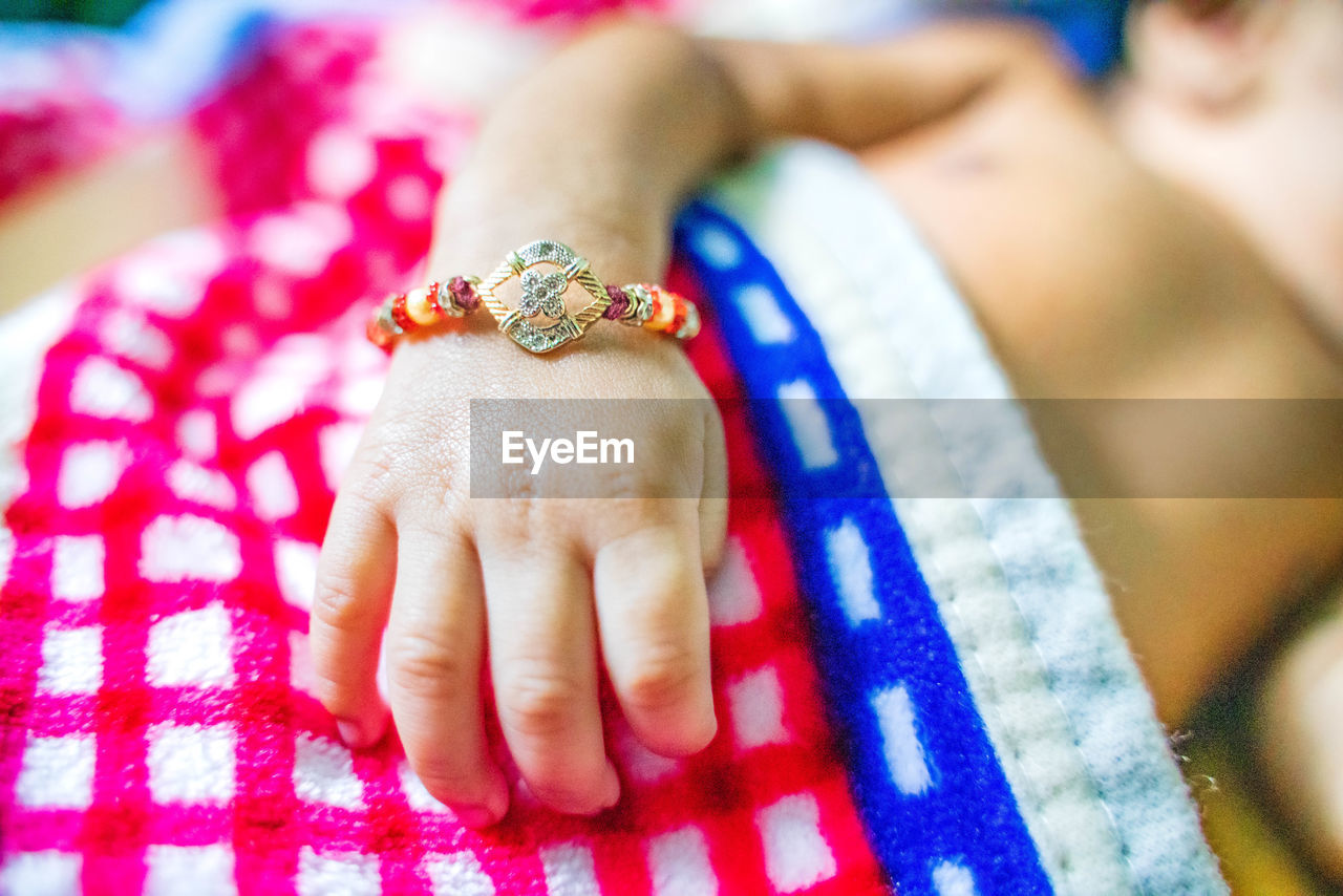 Midsection of baby wearing rakhi