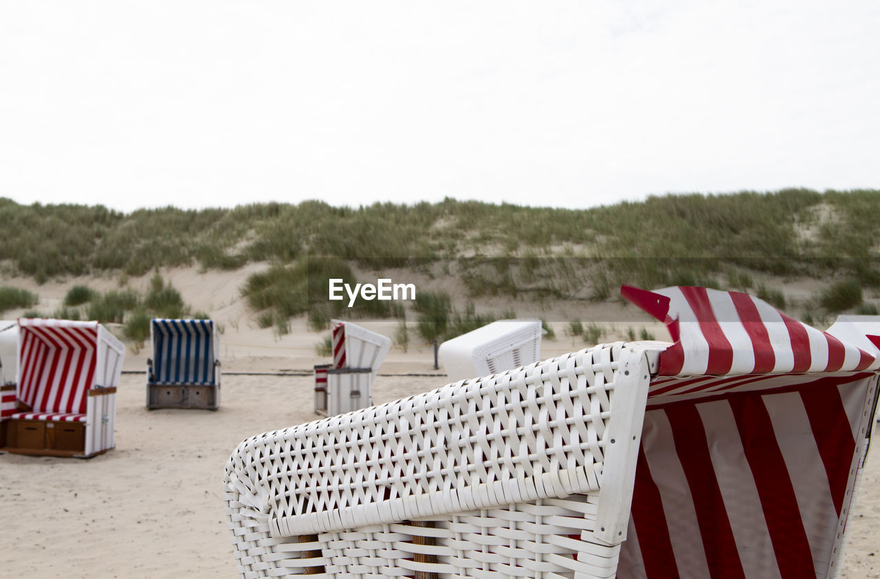 The photo shows some beach chairs on the north sea island baltrum with cloudy sky