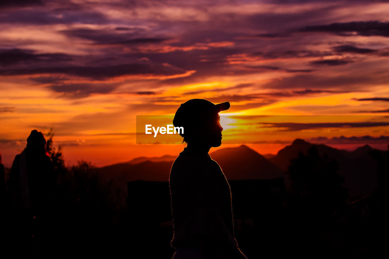 Silhouette woman standing against orange sky during sunset
