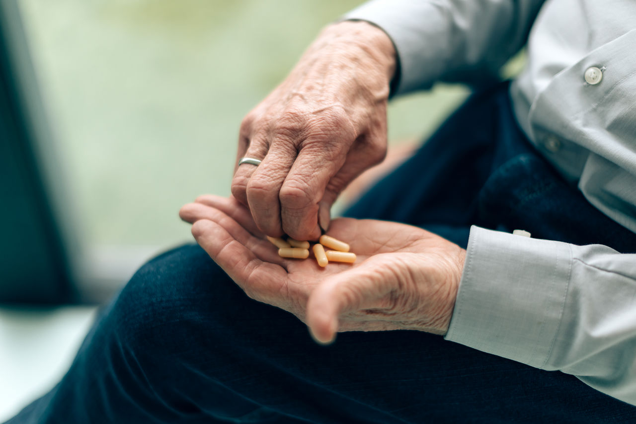 Close up on the hands of an old man taking pills