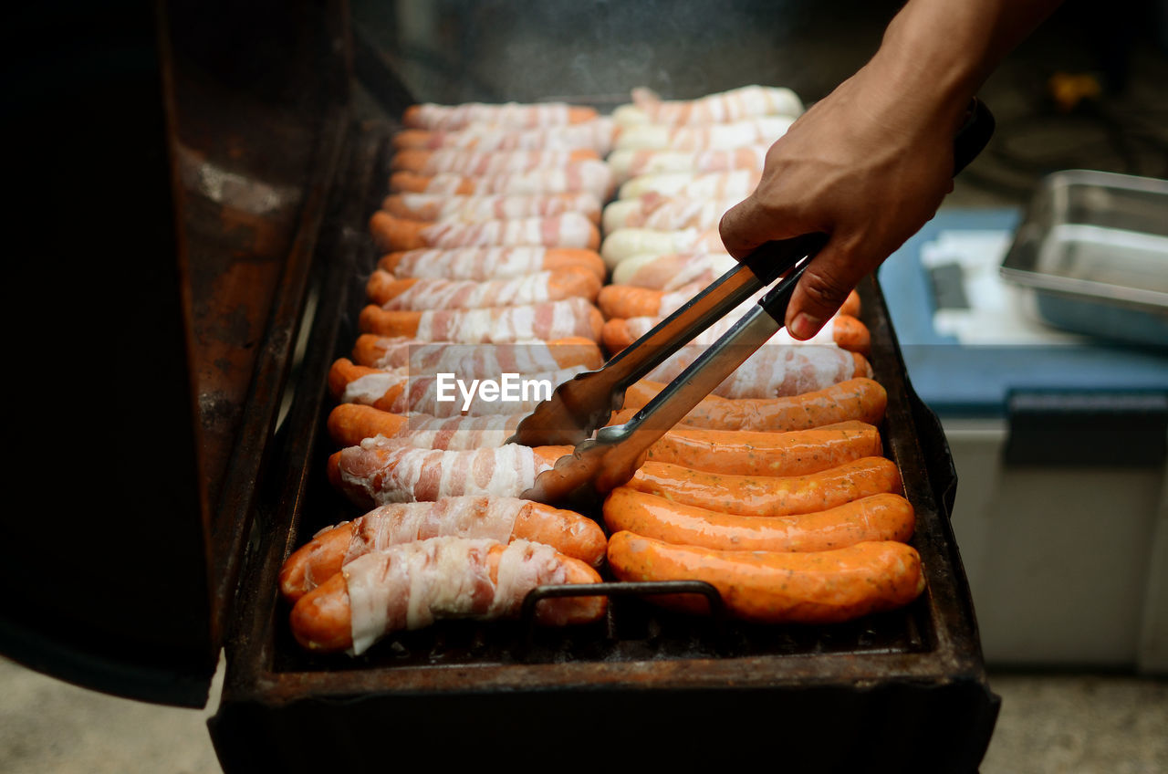 Cropped hand of man preparing food on barbecue grill