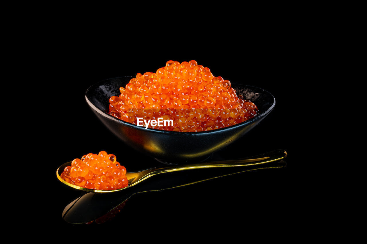 Close-up of orange caviar in black plate
