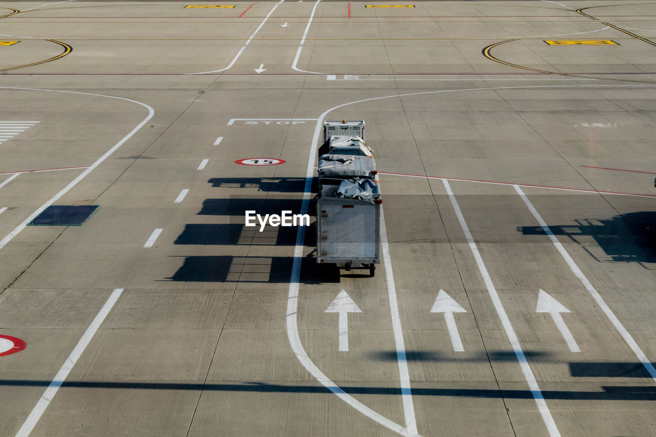 High angle view of luggage carts by arrow sign on runway