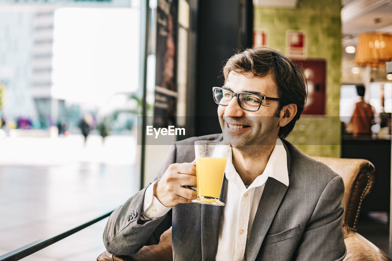 Smiling businessman drinking juice at restaurant