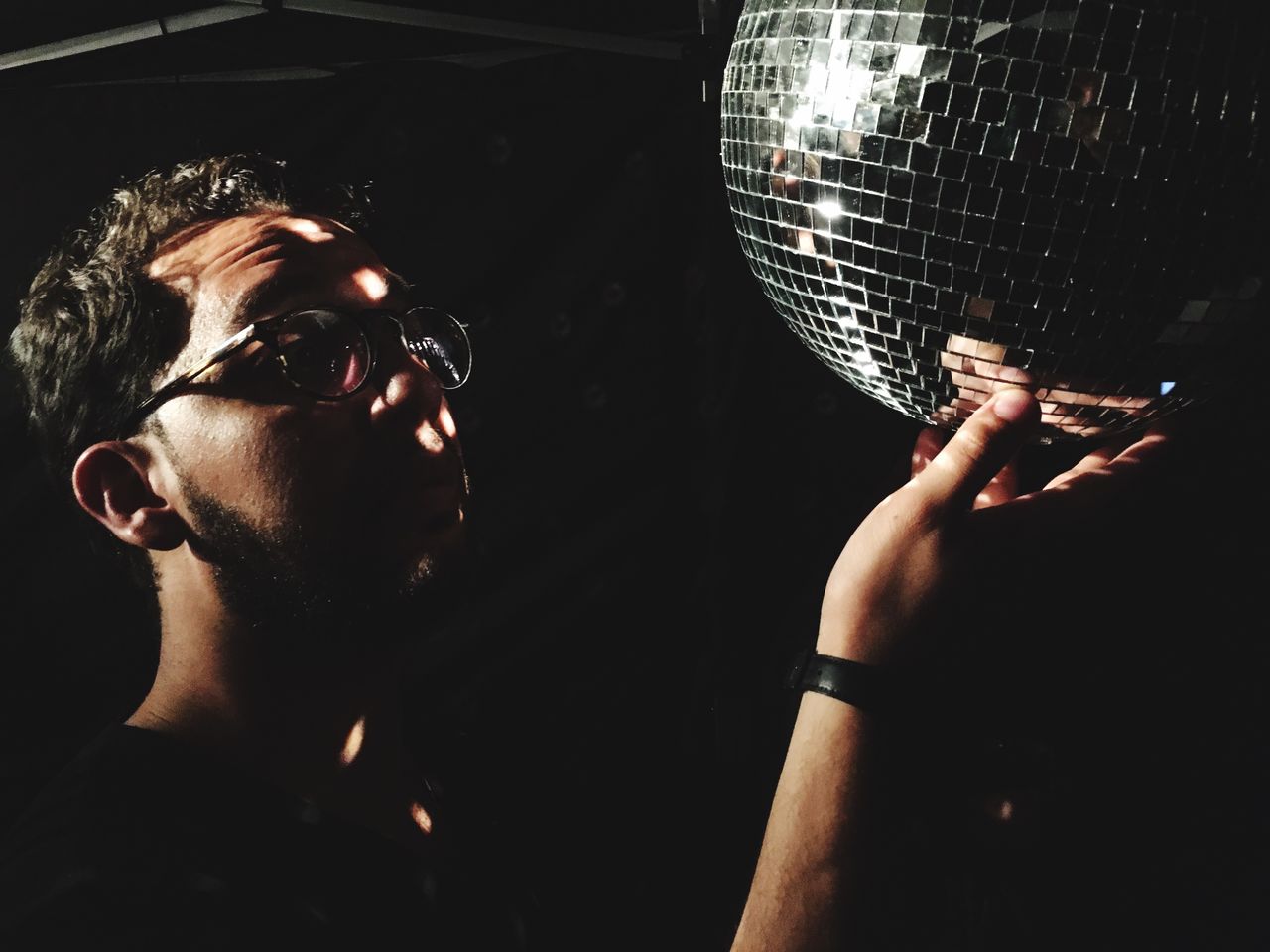 Man touching disco ball in dark