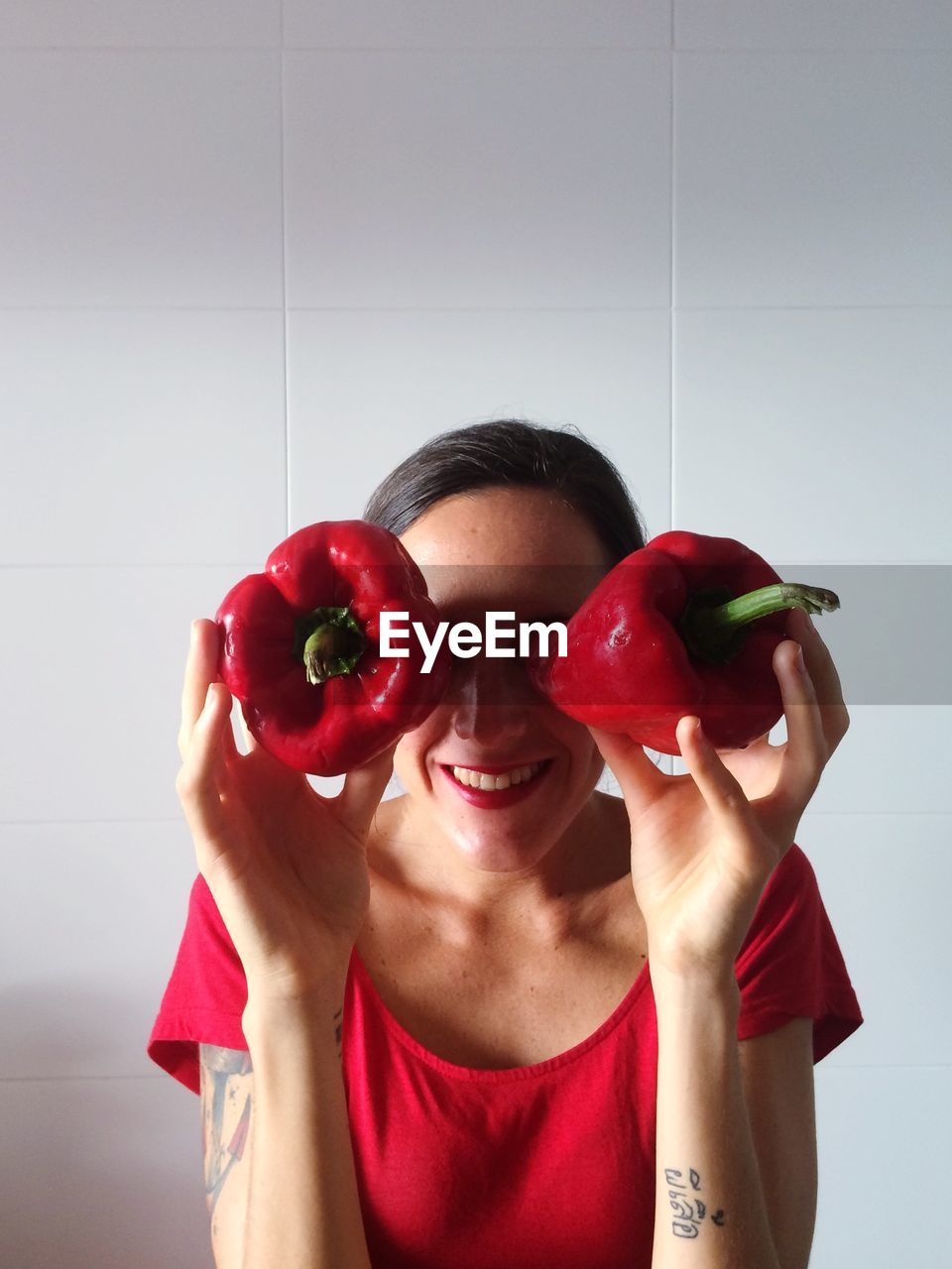 Woman holding red capsicum as eyes at home