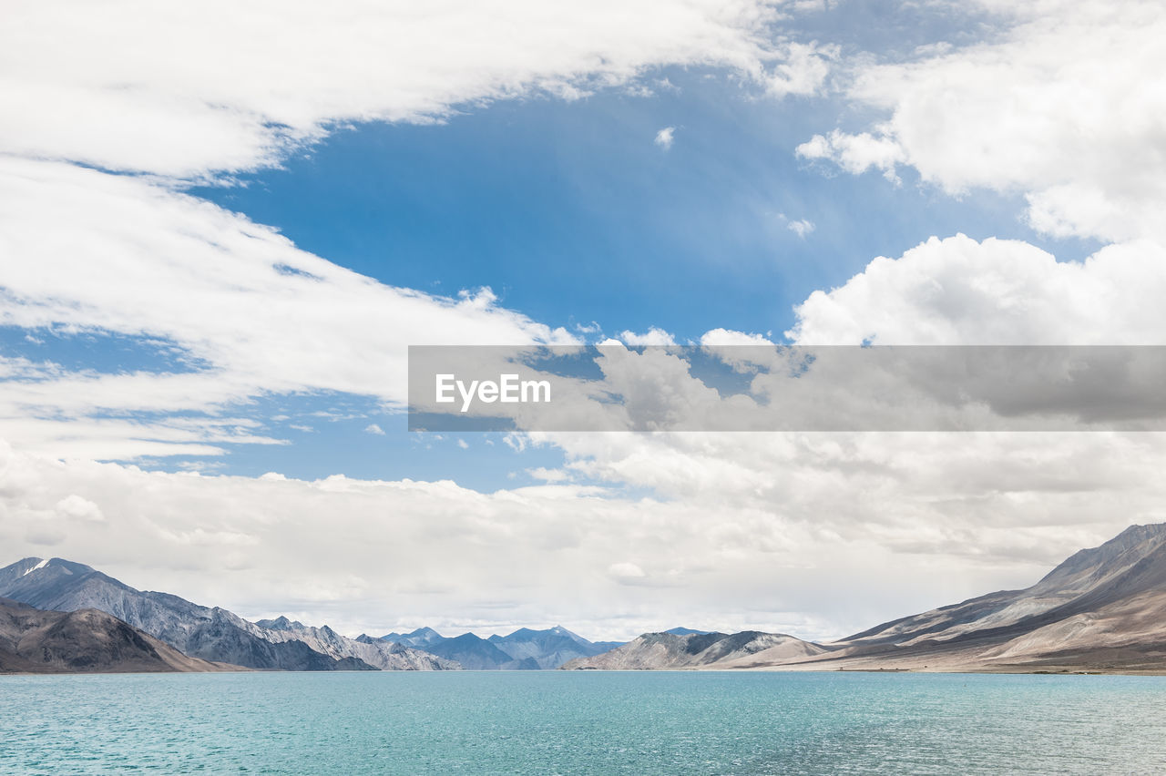 Scenic view of pangong lake by mountains against cloudy sky