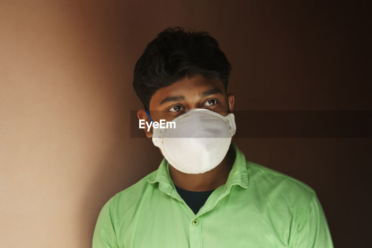 Young man with mask against wall