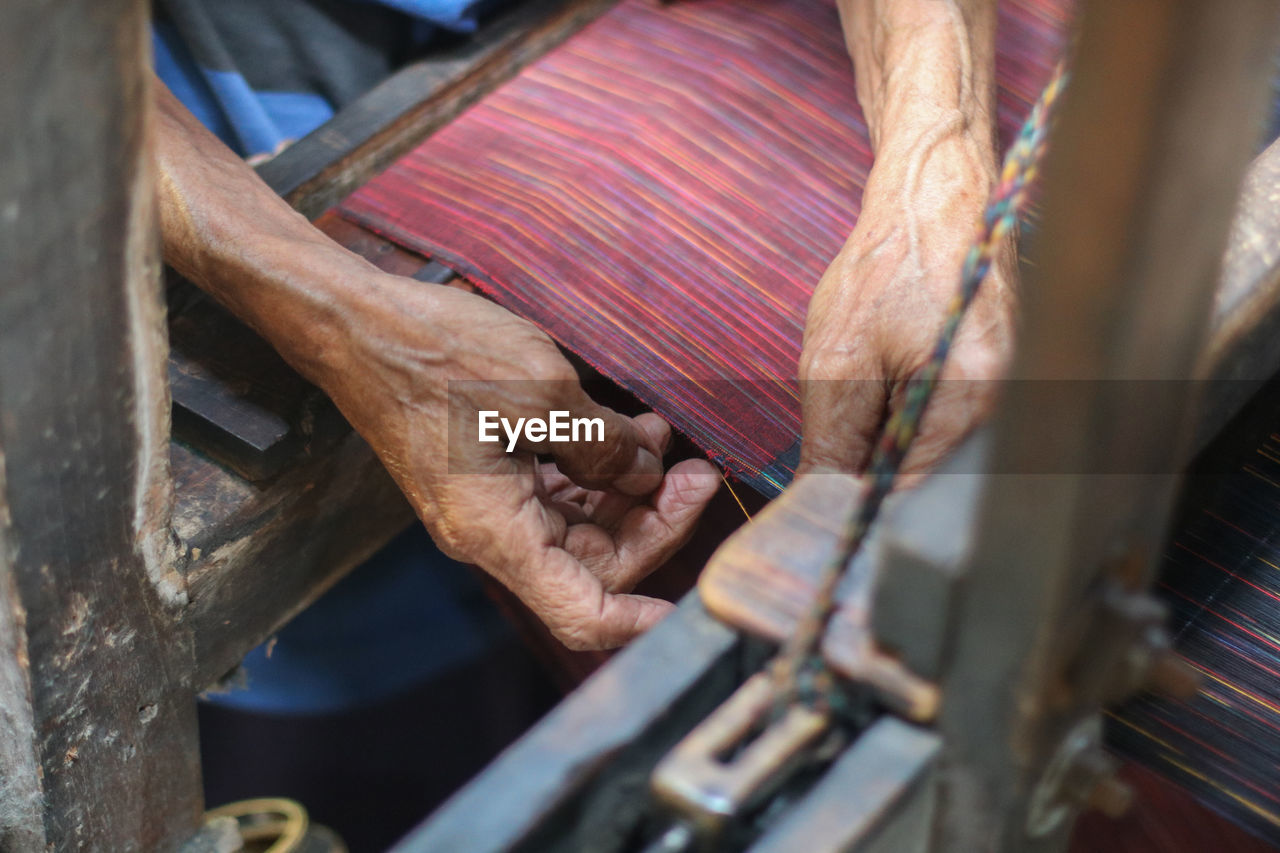 Cropped hands of senior person working at textile industry
