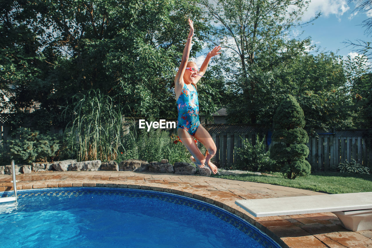 Girl child diving jumping in water on home backyard pool. summer outdoor water activity for kids.