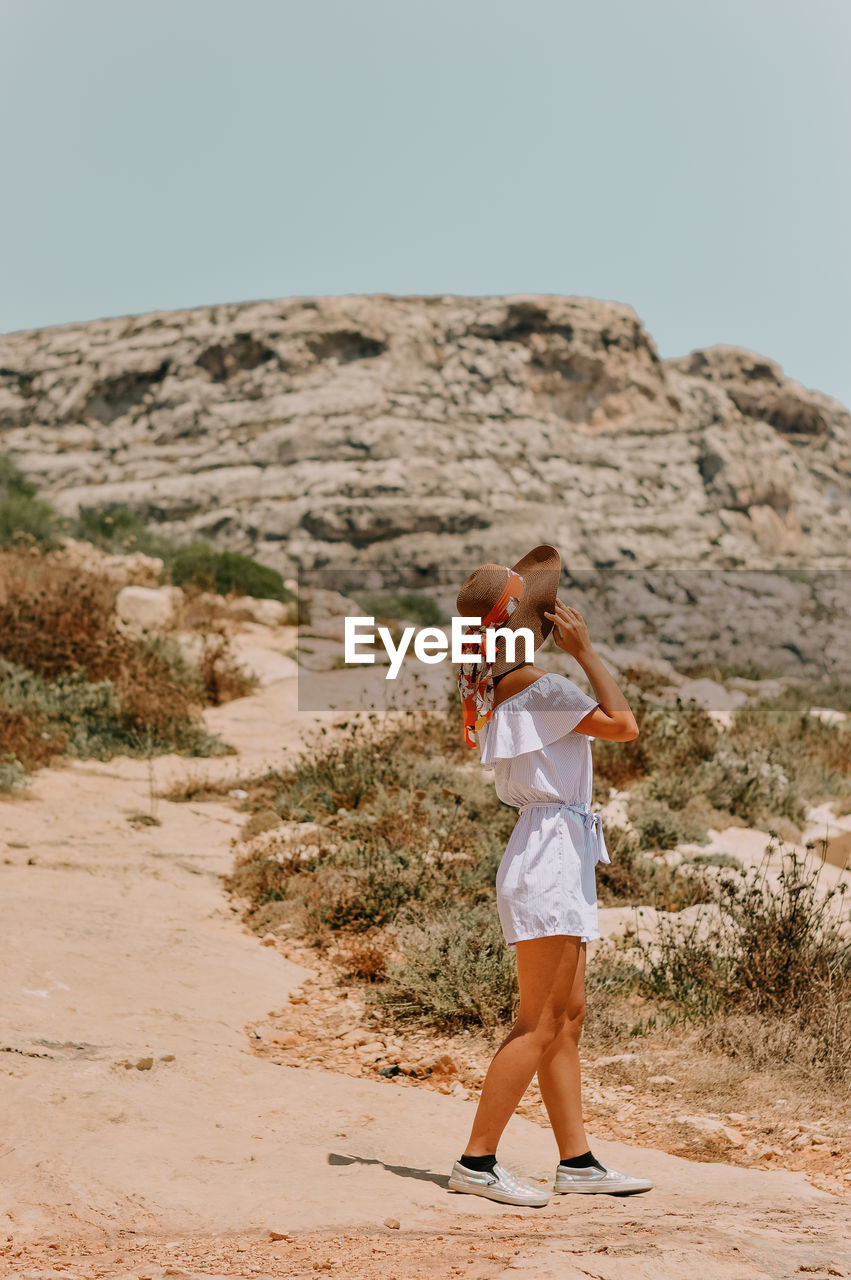 Side view of woman standing on land against clear sky