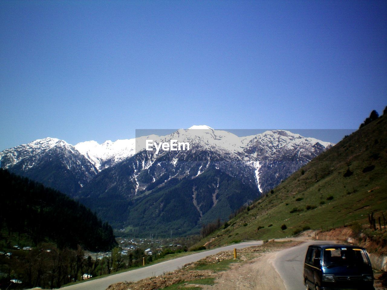 ROAD BY SNOWCAPPED MOUNTAINS AGAINST CLEAR SKY