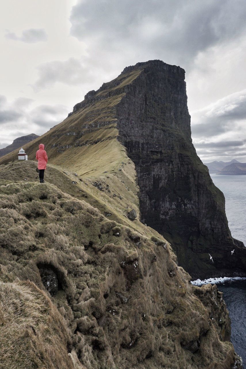 Rear view of person climbing on mountain by sea