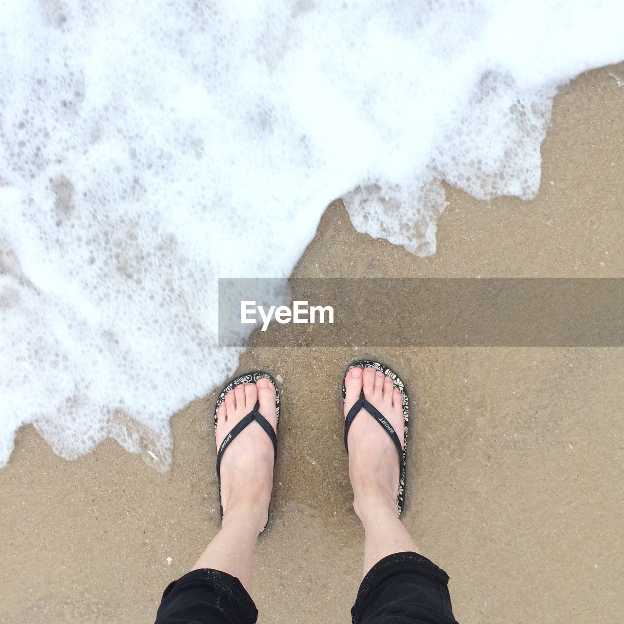 Low section of woman standing on beach