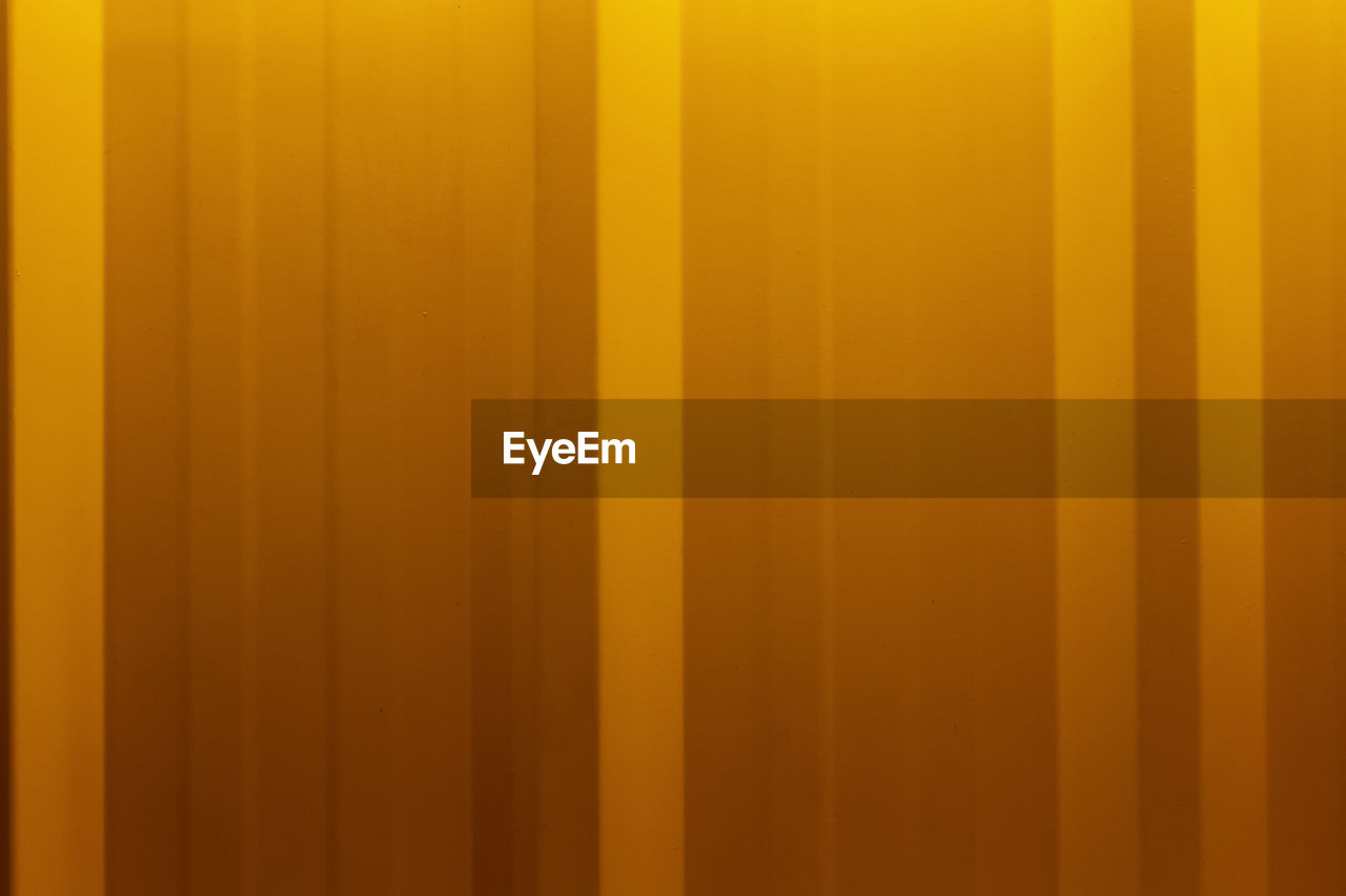 FULL FRAME SHOT OF YELLOW WALL WITH ORANGE CURTAIN