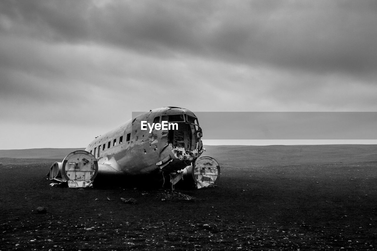 Airplane wreckage at solheimasandur beach against cloudy sky