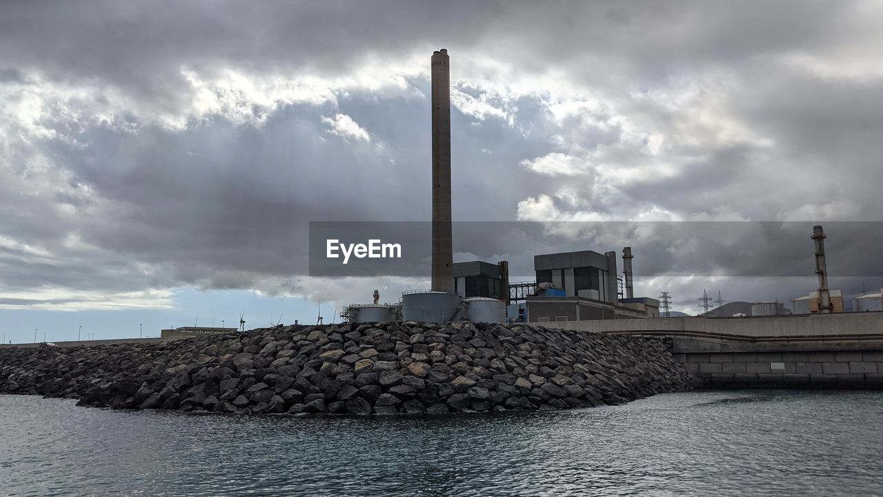 cloud, water, sky, architecture, sea, industry, built structure, factory, tower, environment, nature, environmental issues, breakwater, smoke stack, building exterior, coast, vehicle, power station, no people, outdoors, power generation, pollution, social issues, ocean, horizon, business finance and industry, day, storm