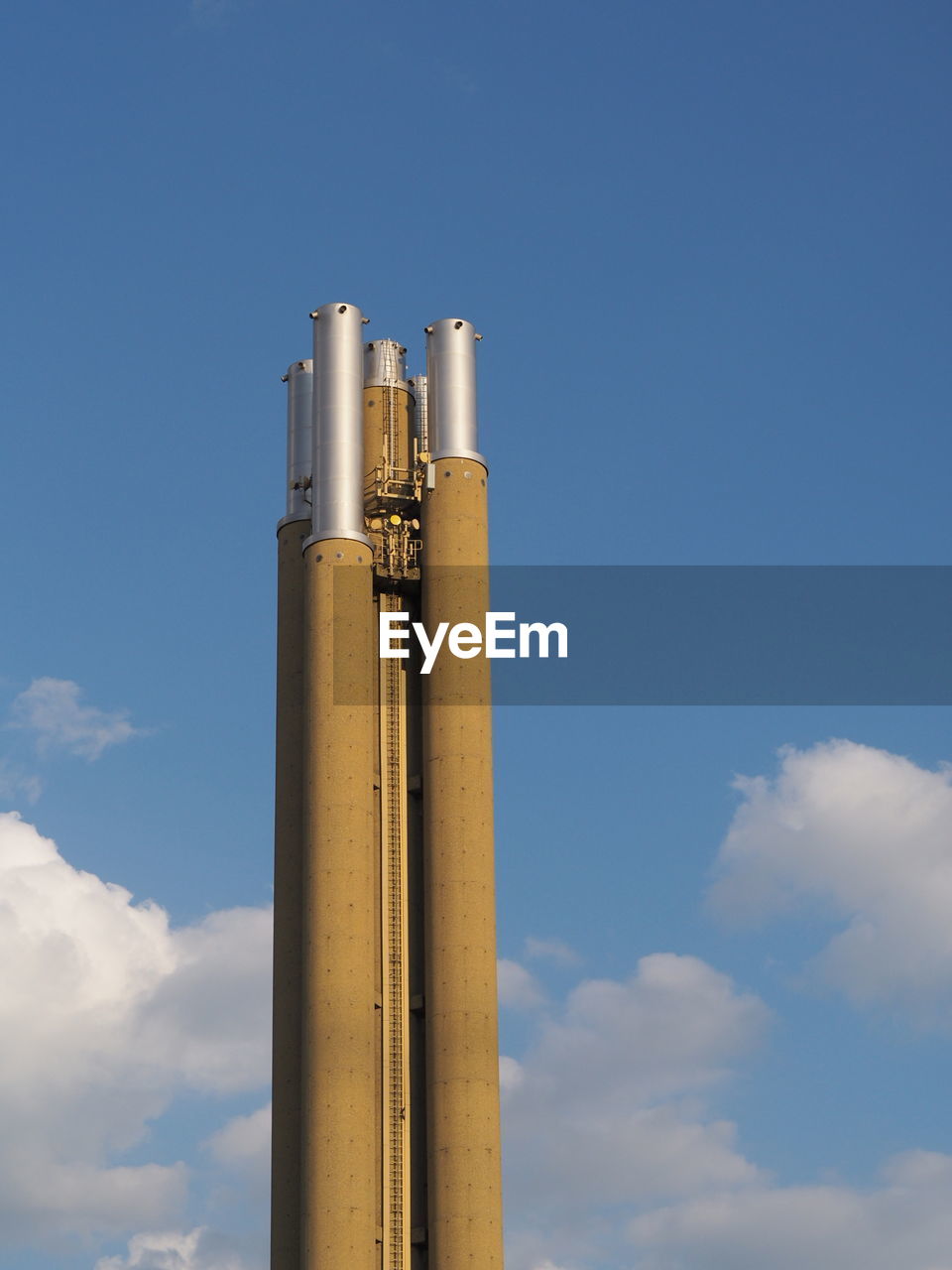 LOW ANGLE VIEW OF SMOKE STACKS AGAINST BLUE SKY