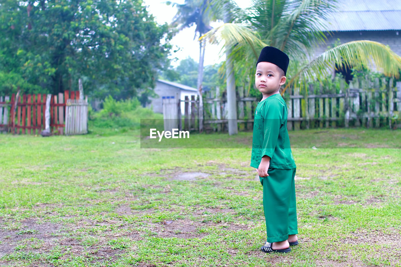 Full length portrait of boy in traditional clothing standing on field
