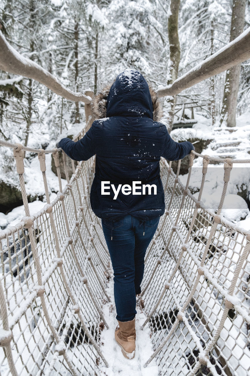 Rear view of person on snow covered footbridge