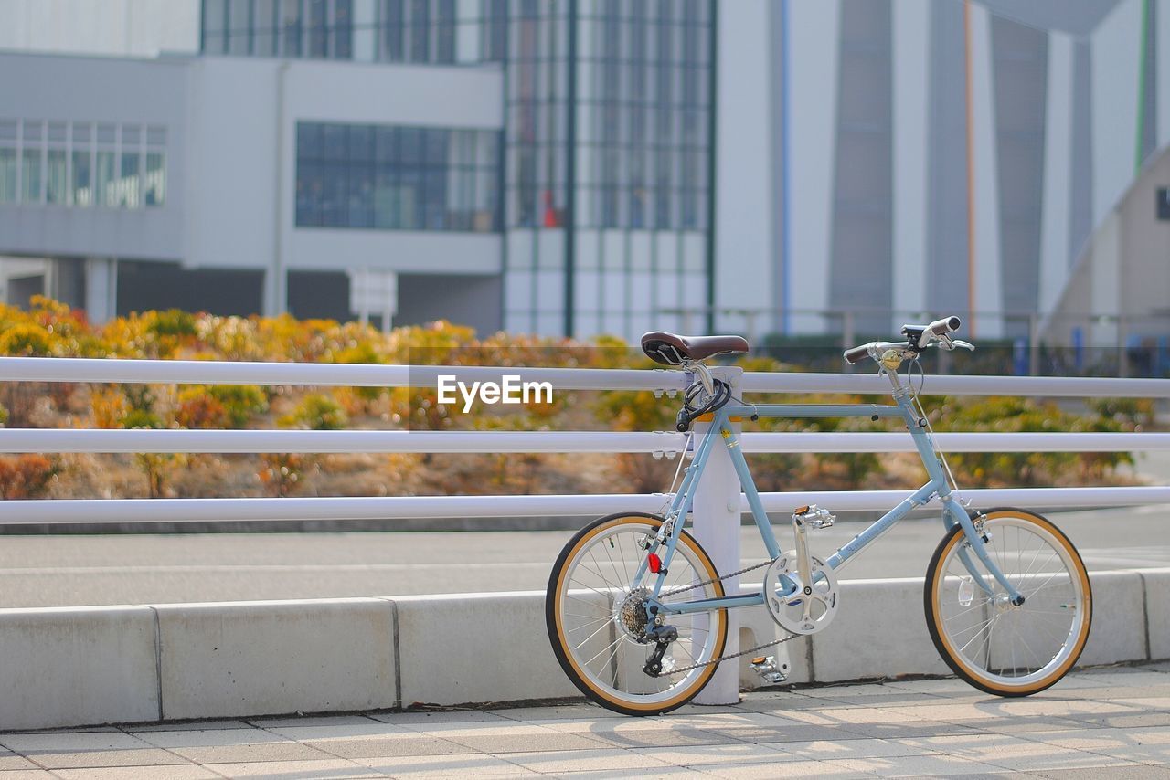 Bicycle parked by railing against building