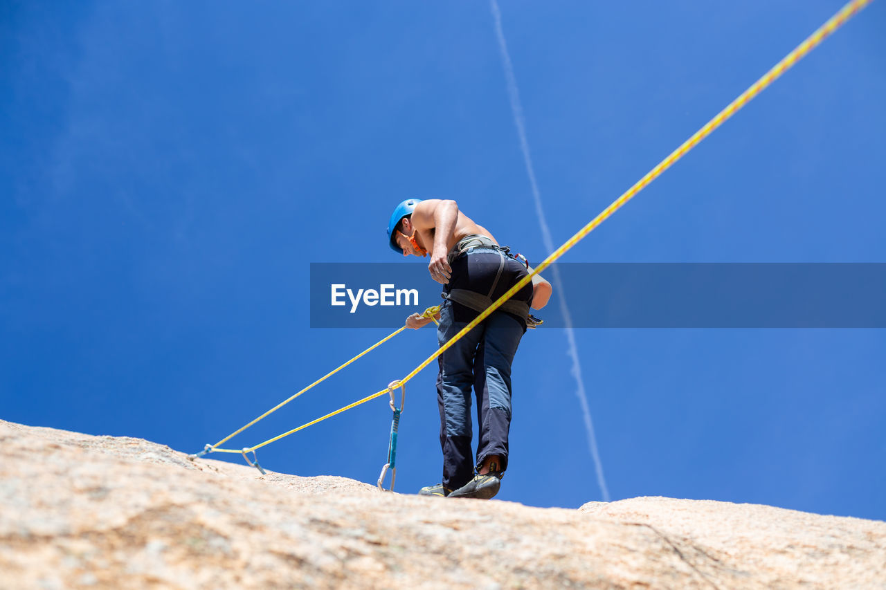 Rear view of shirtless man climbing rock