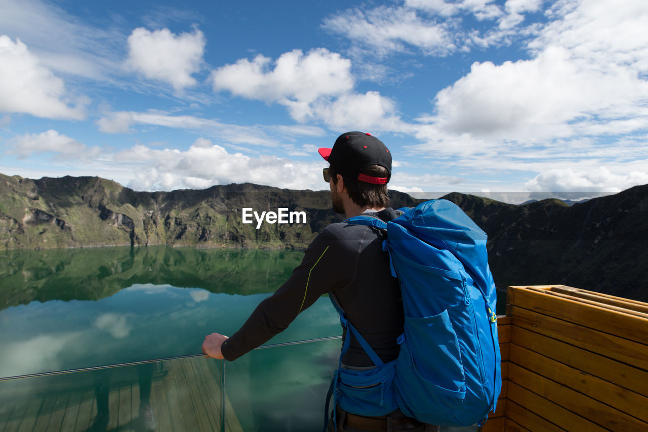 Man looking at lake by mountains