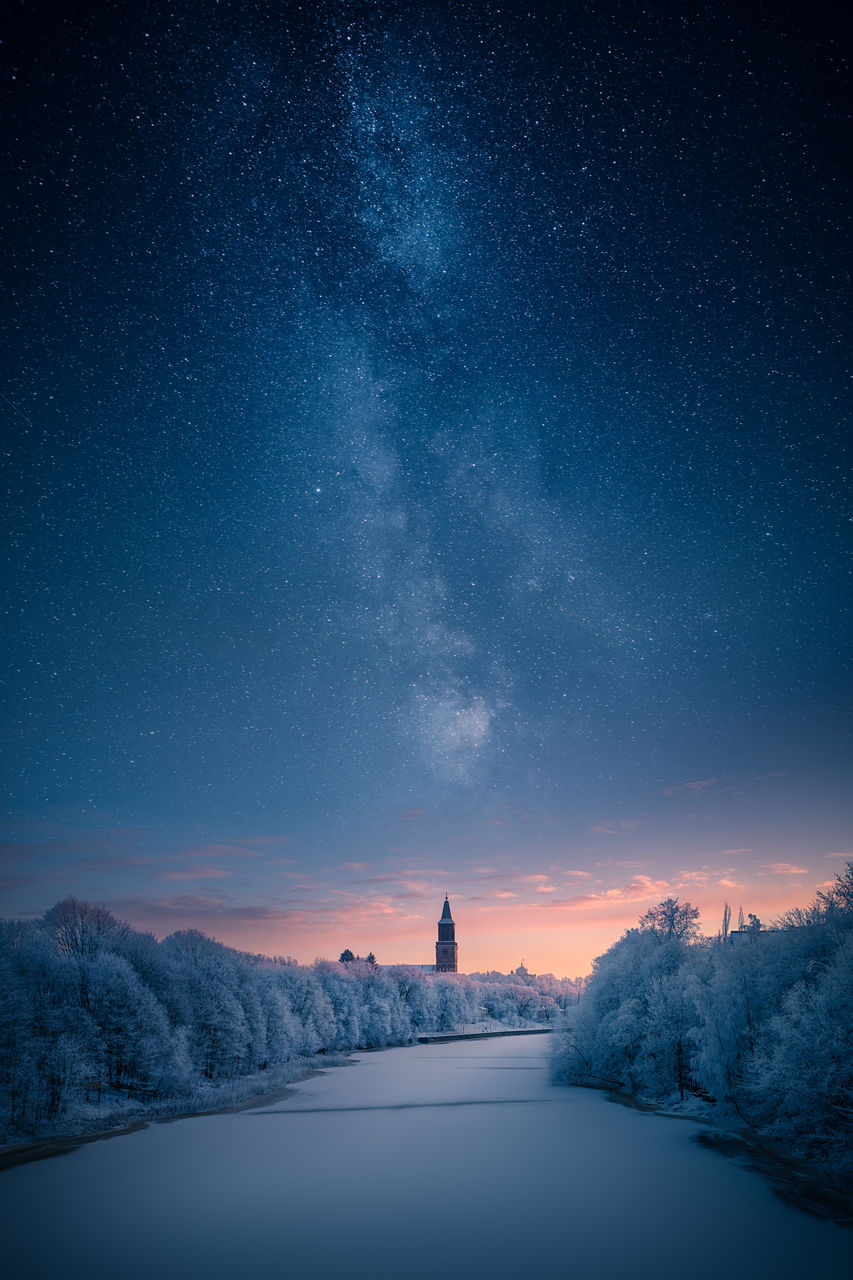 Frozen river and trees against star field