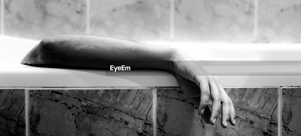 Cropped hand of man drowning in bathtub