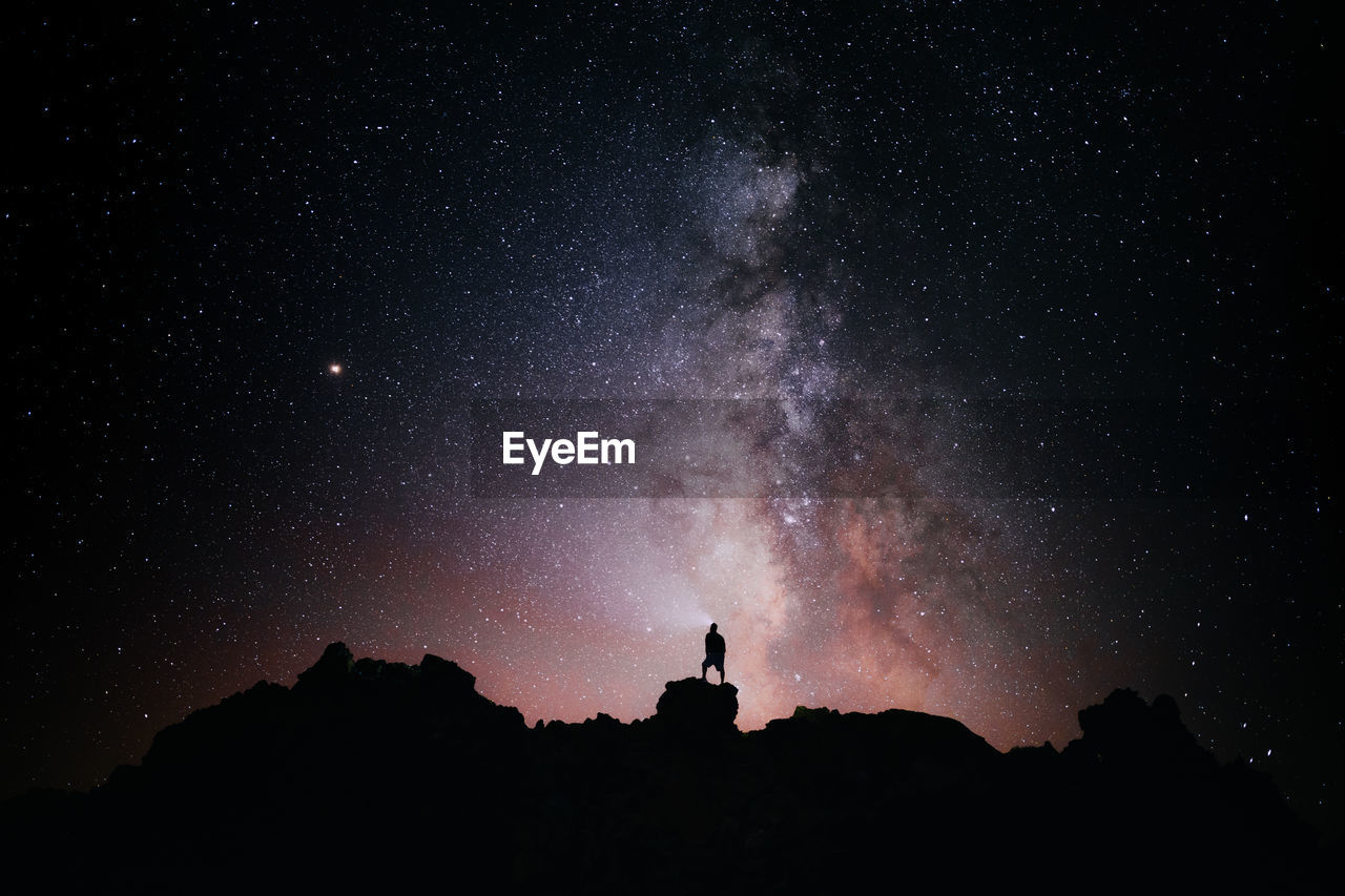 A person standing looking at the star field and the milky way