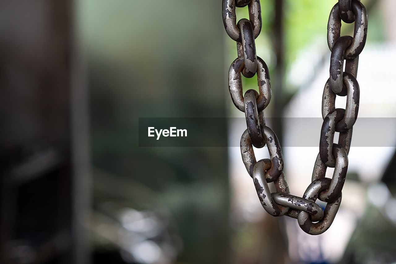 CLOSE-UP OF RUSTY CHAIN HANGING ON METAL FENCE