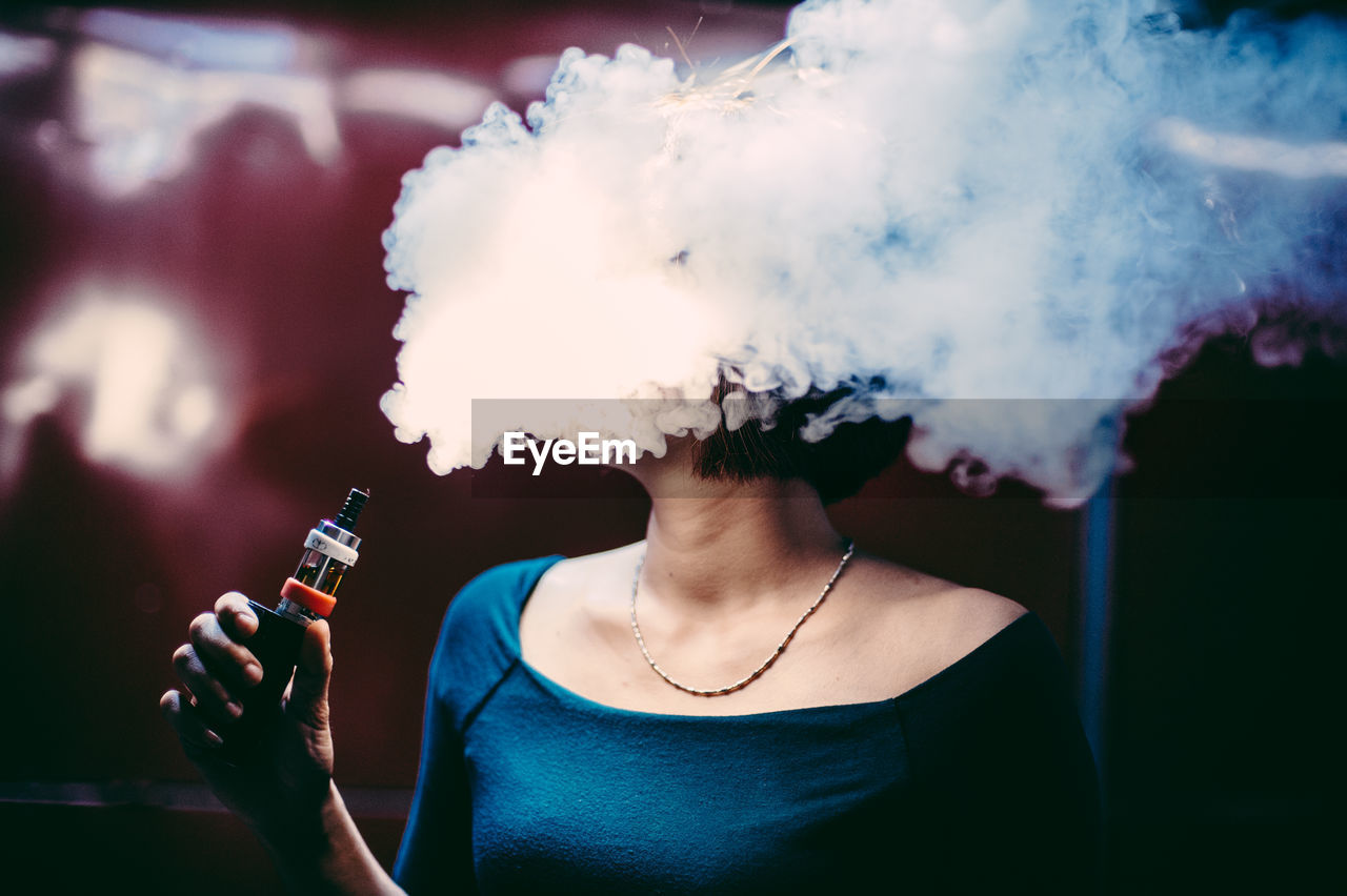 Woman emitting smoke while smoking at home
