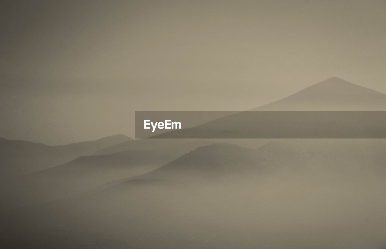 Mountains covered with fog against clear sky