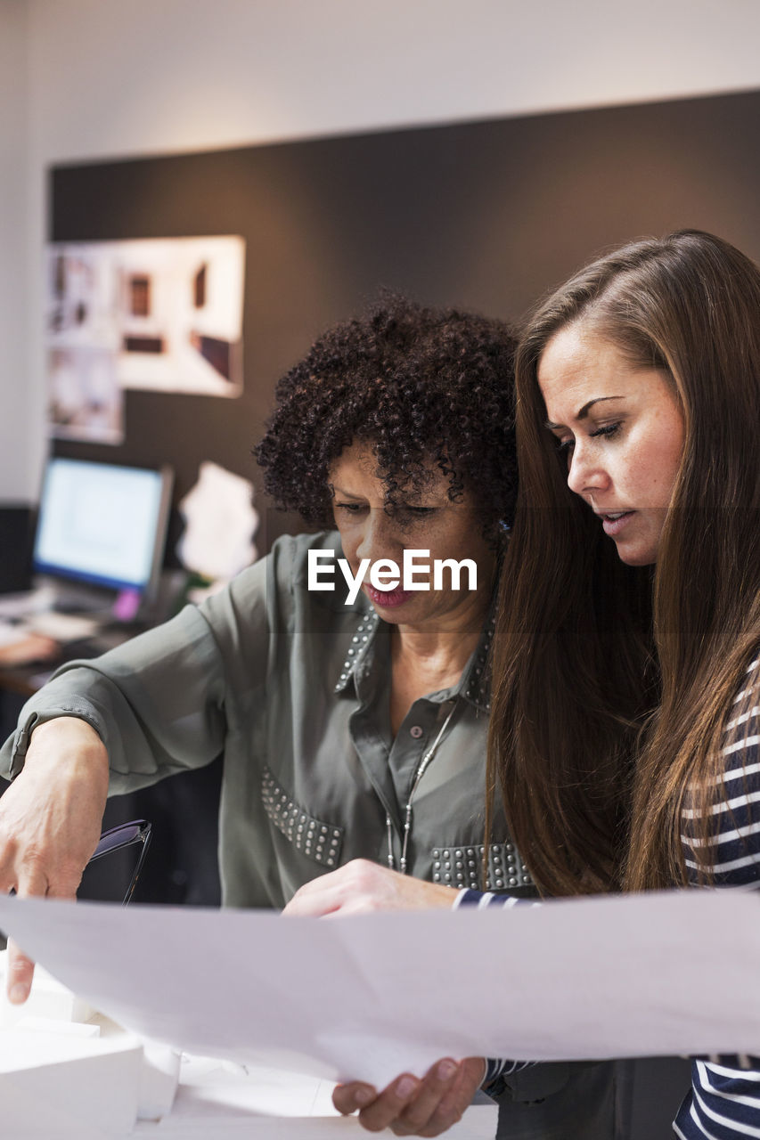 Businesswomen discussing over blueprint in office