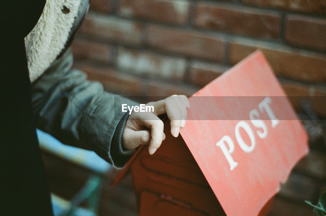 Cropped image of person touching public mailbox