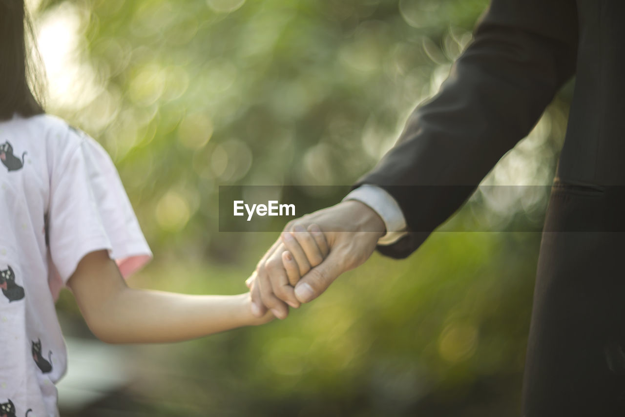 CLOSE-UP OF COUPLE HOLDING HANDS OF BABY