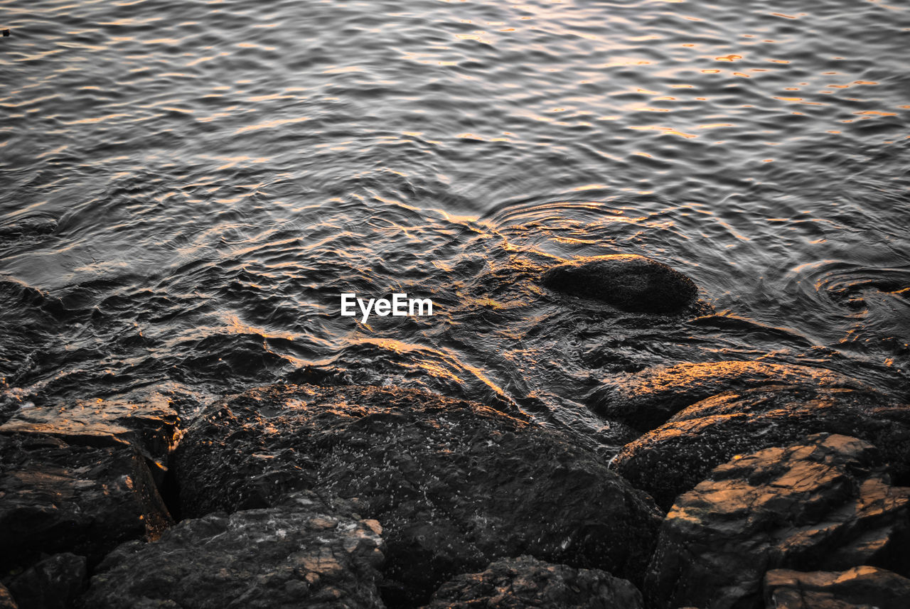 High angle view of rocks in sea at sunset