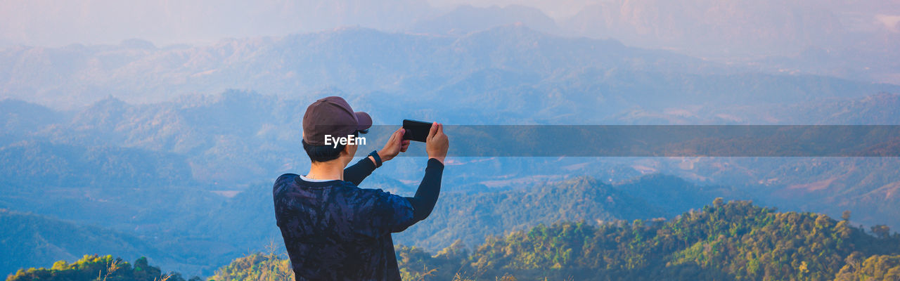 Rear view of person photographing on mountain