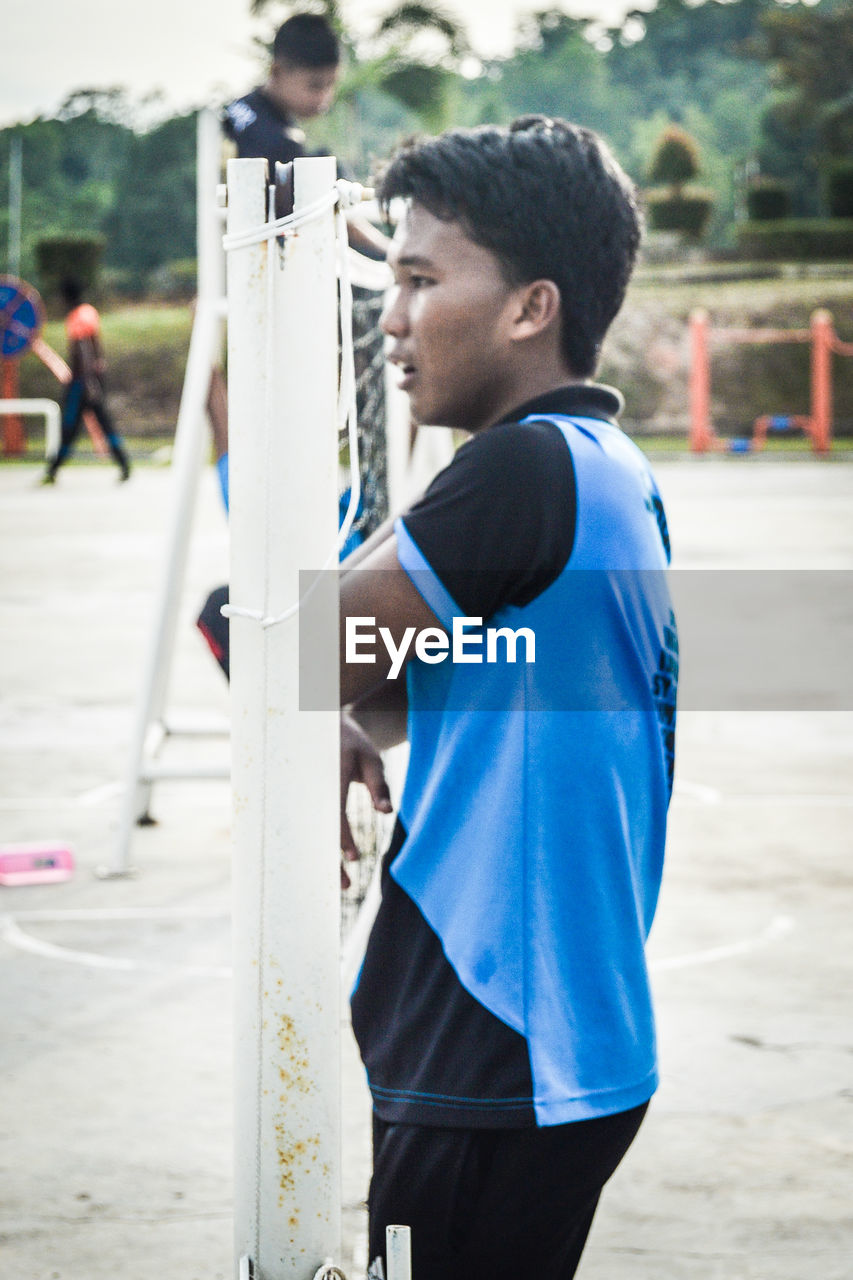 Side view of young man standing at playground