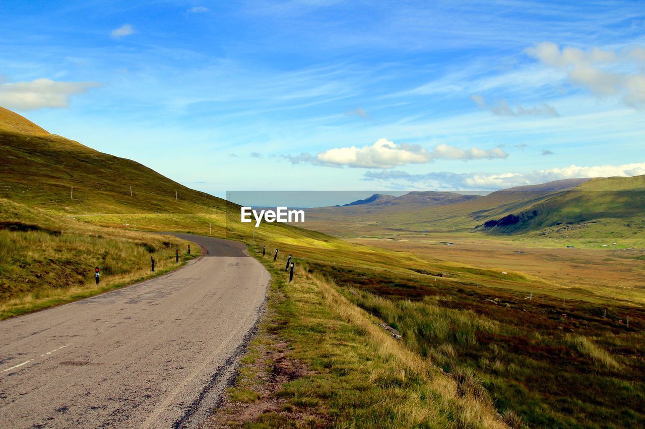 Road leading towards mountains against sky