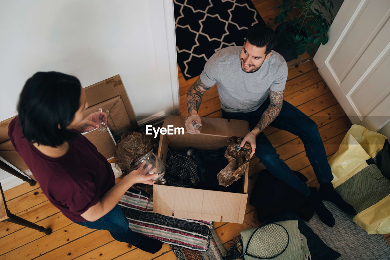 High angle view of man and woman unpacking box in living room