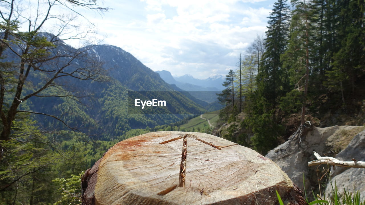 Scenic view of mountains against sky with arrow pointing way carved on wood